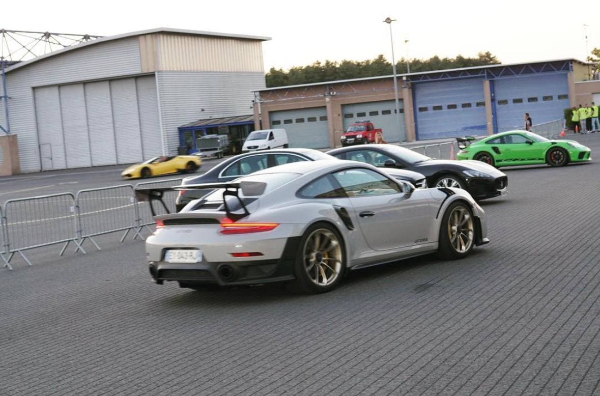 Performance cars moving through a circuit paddock